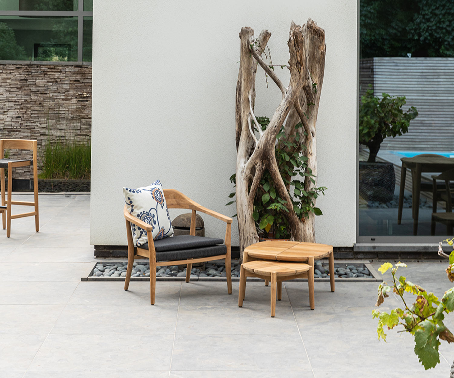 Table d'extérieur carrée Oasiq Copenhagen avec chaise et arbre sur la terrasse Table d'extérieur carrée Oasiq Copenhagen avec chaise et arbre sur la terrasse