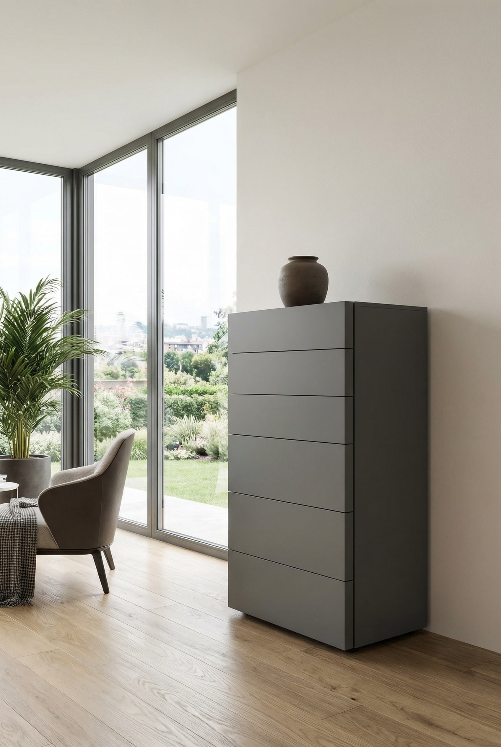Une commode haute moderne sans poign&eacute;e en gris fonc&eacute; mat &eacute;l&eacute;gant, mise en sc&egrave;ne devant un mur clair comme un meuble minimaliste et contrast&eacute;.