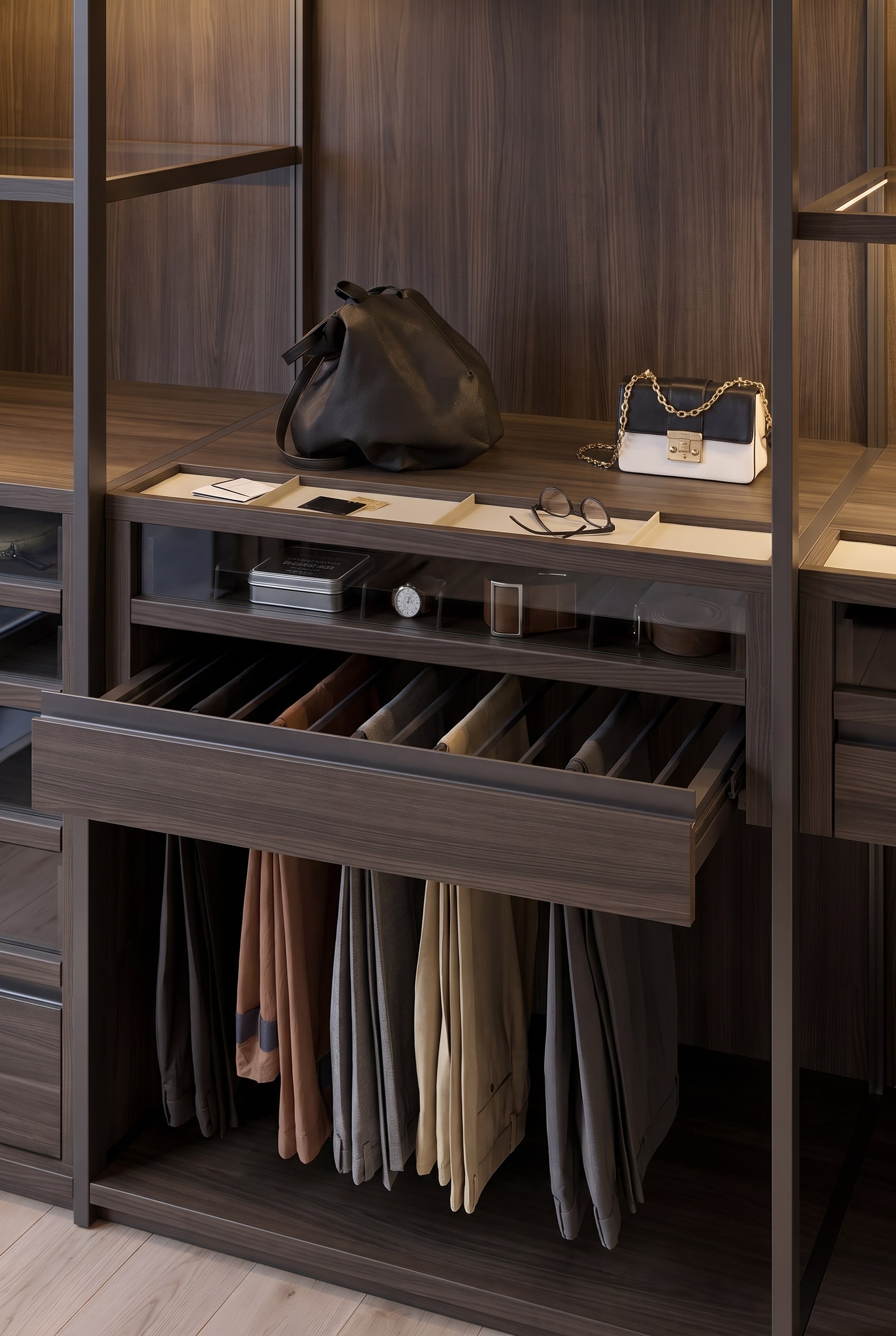 Detailaufnahme einer geöffneten Schublade im Holzdekor mit integriertem Hosennauszug und flacher Accessoire-Ablage darüber.