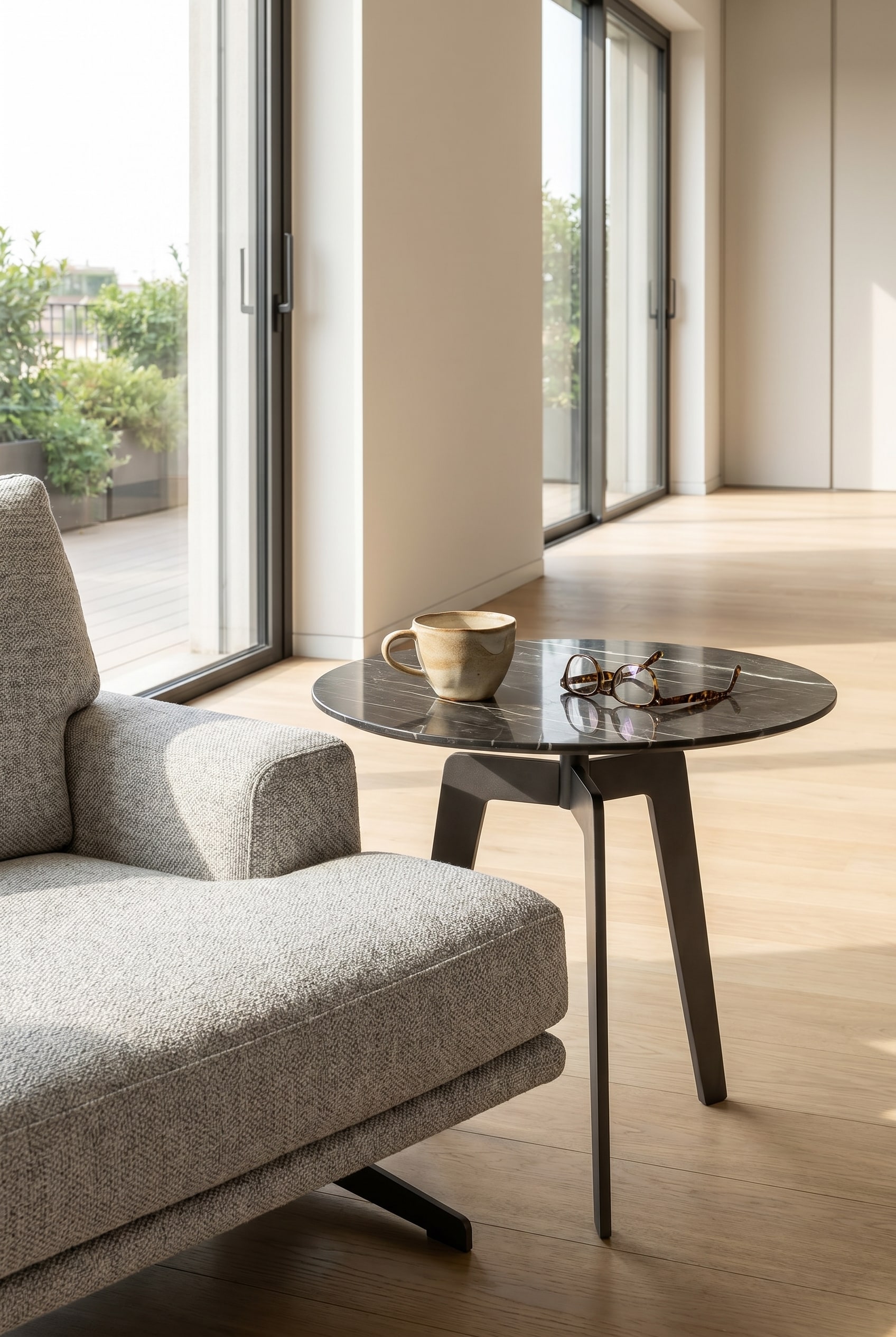 Minimalistischer Lotus Beistelltisch in Marmoroptik neben einem Loungesessel mit einer weißen Kaffeetasse