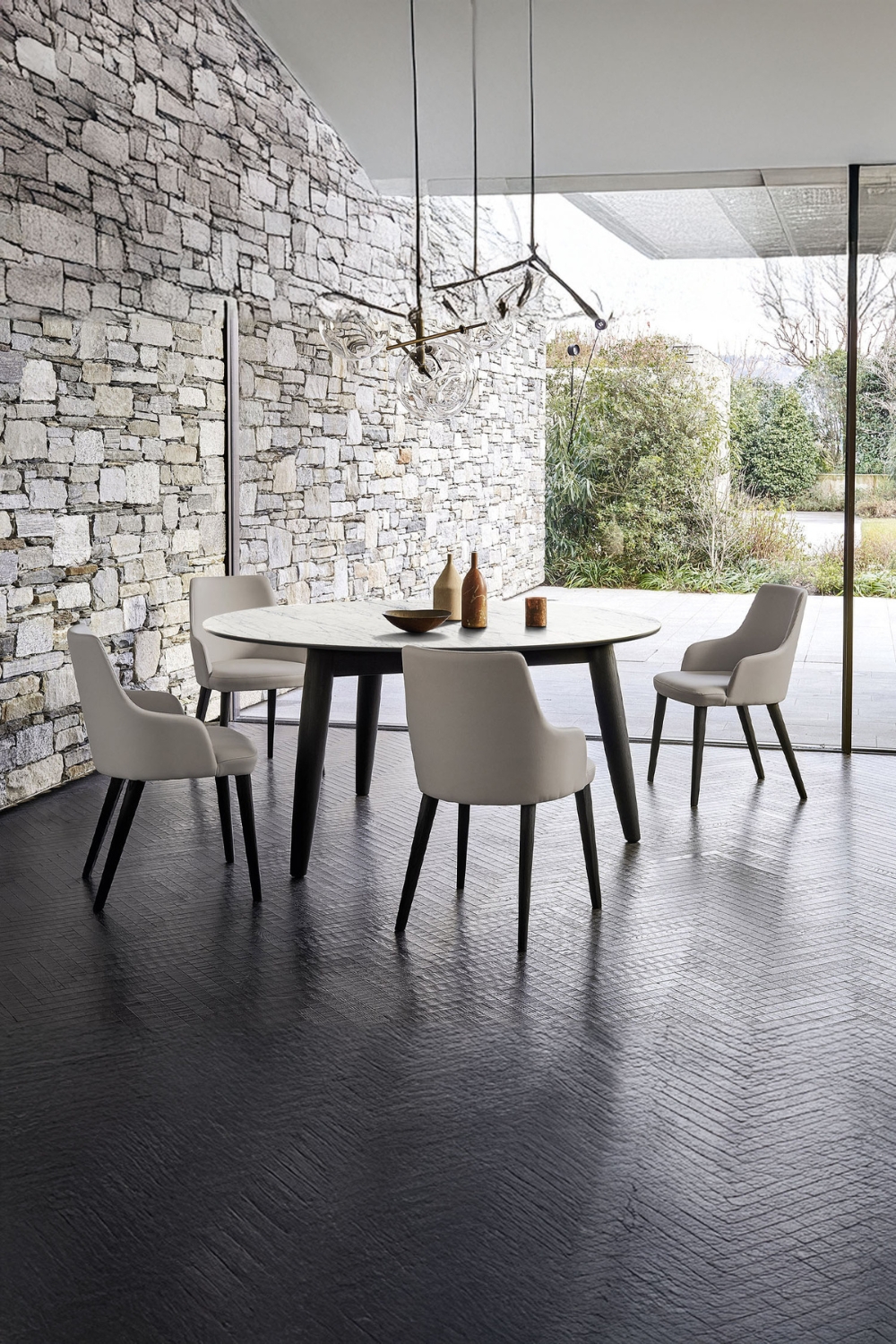 table à manger ronde et chaises courbes en noir et blanc à côté d'un mur effet pierre