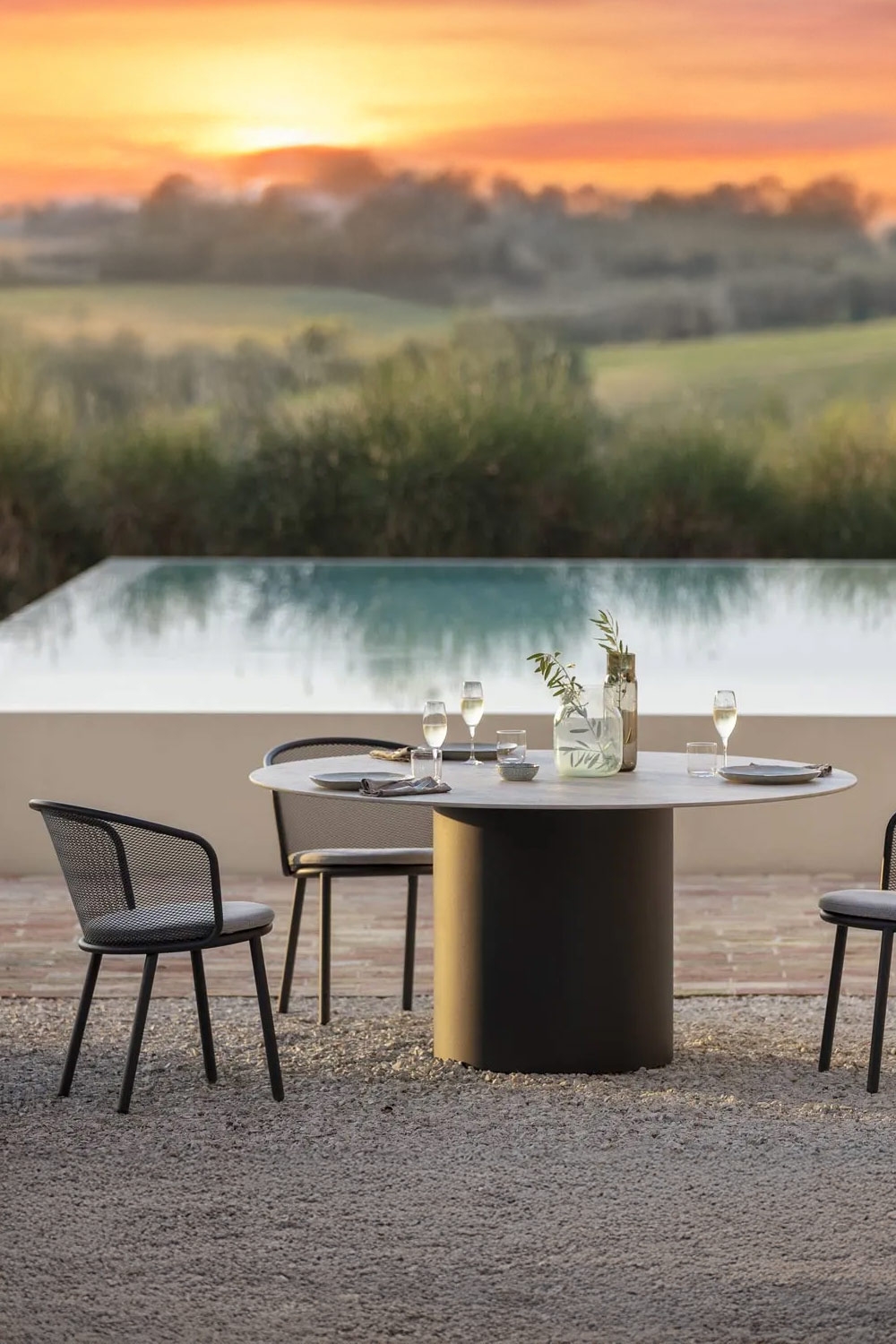 table-de-jardin-ronde-avec-chaises-modernes-devant-une-grande-piscine