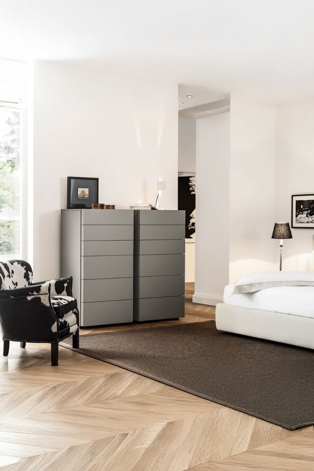 commode à tiroirs moderne avec façades sans poignées entre un lit élégant et un fauteuil extravagant