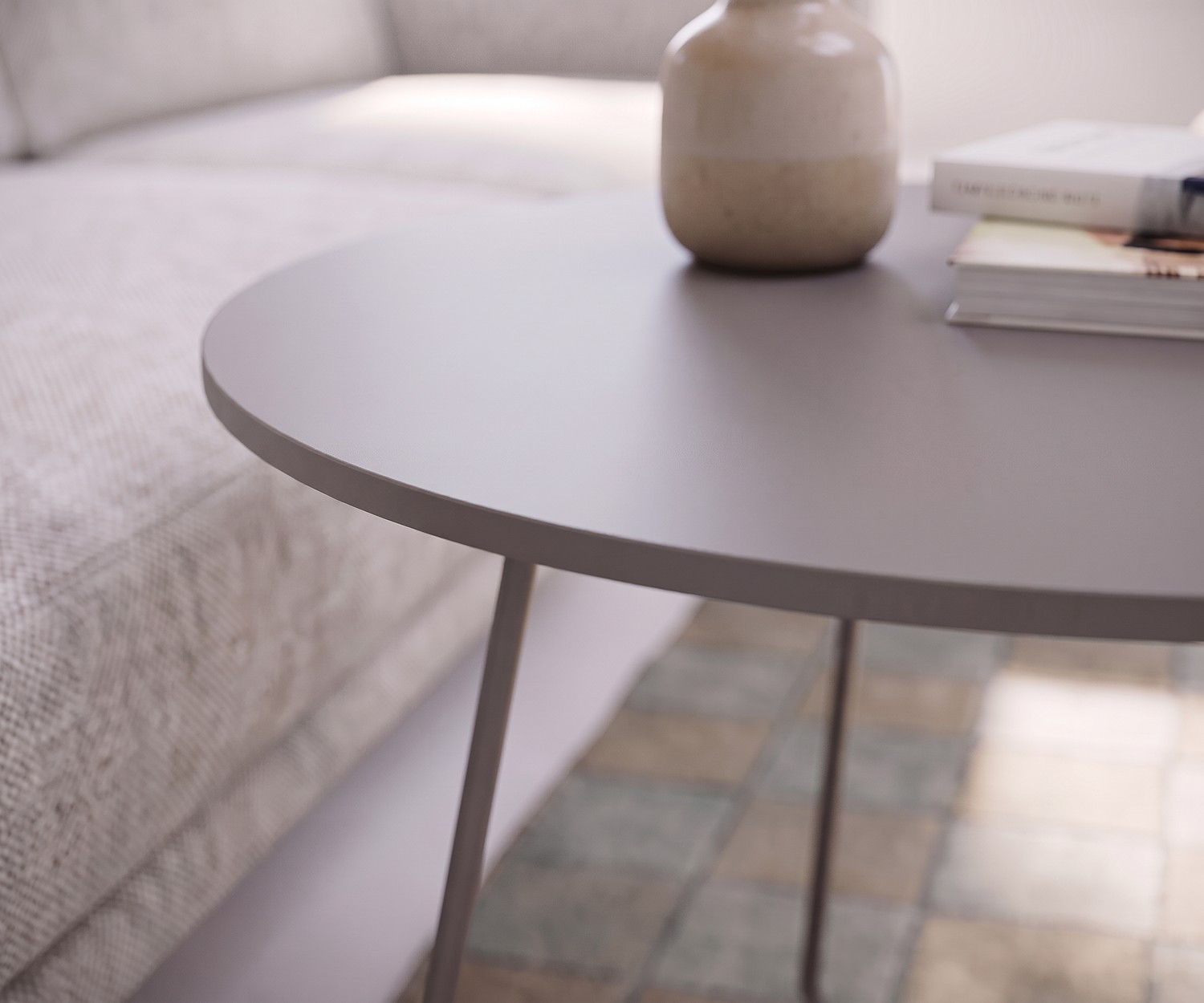 Table basse Orbis Novamobili comme table d'appoint de salon près du canapé, plateau rond gris mat avec un vase.