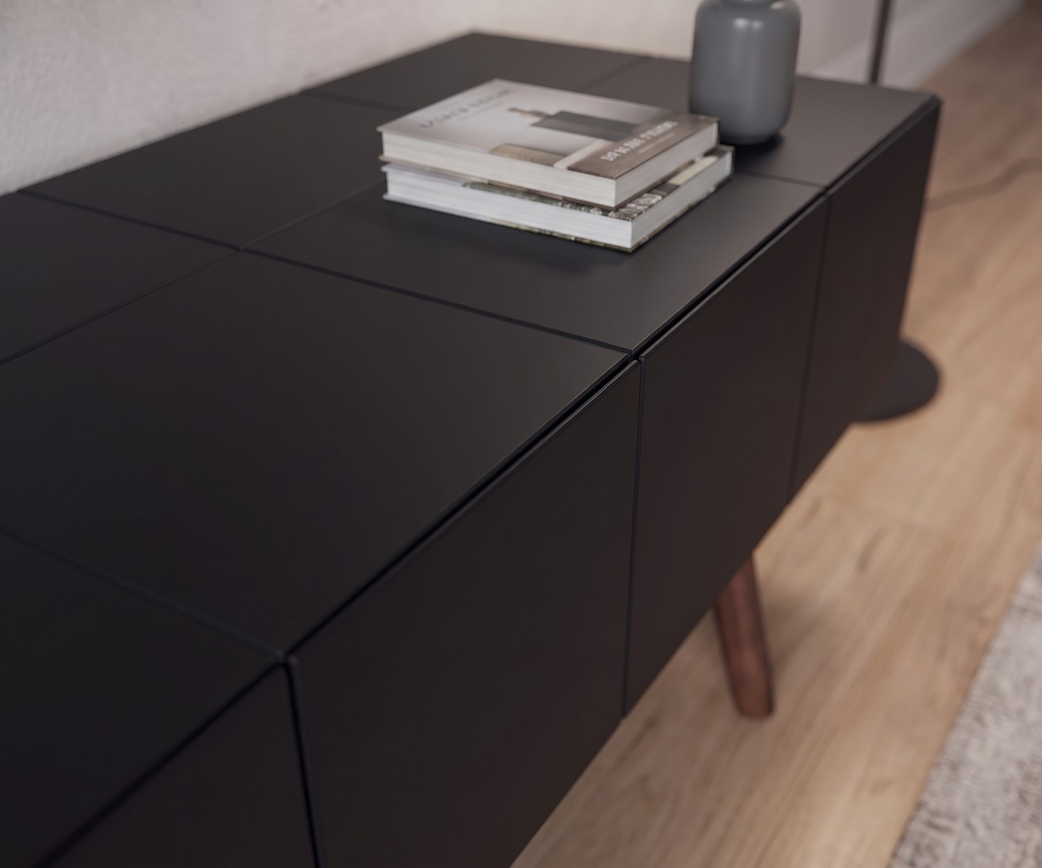 Meuble bas design al2 MOS-I-KO 005 B noir mat Meuble TV bas al2 MOS-I-KO 005 B noir mat, gros plan sur la façade sans poignée et les pieds en bois de style rétro.