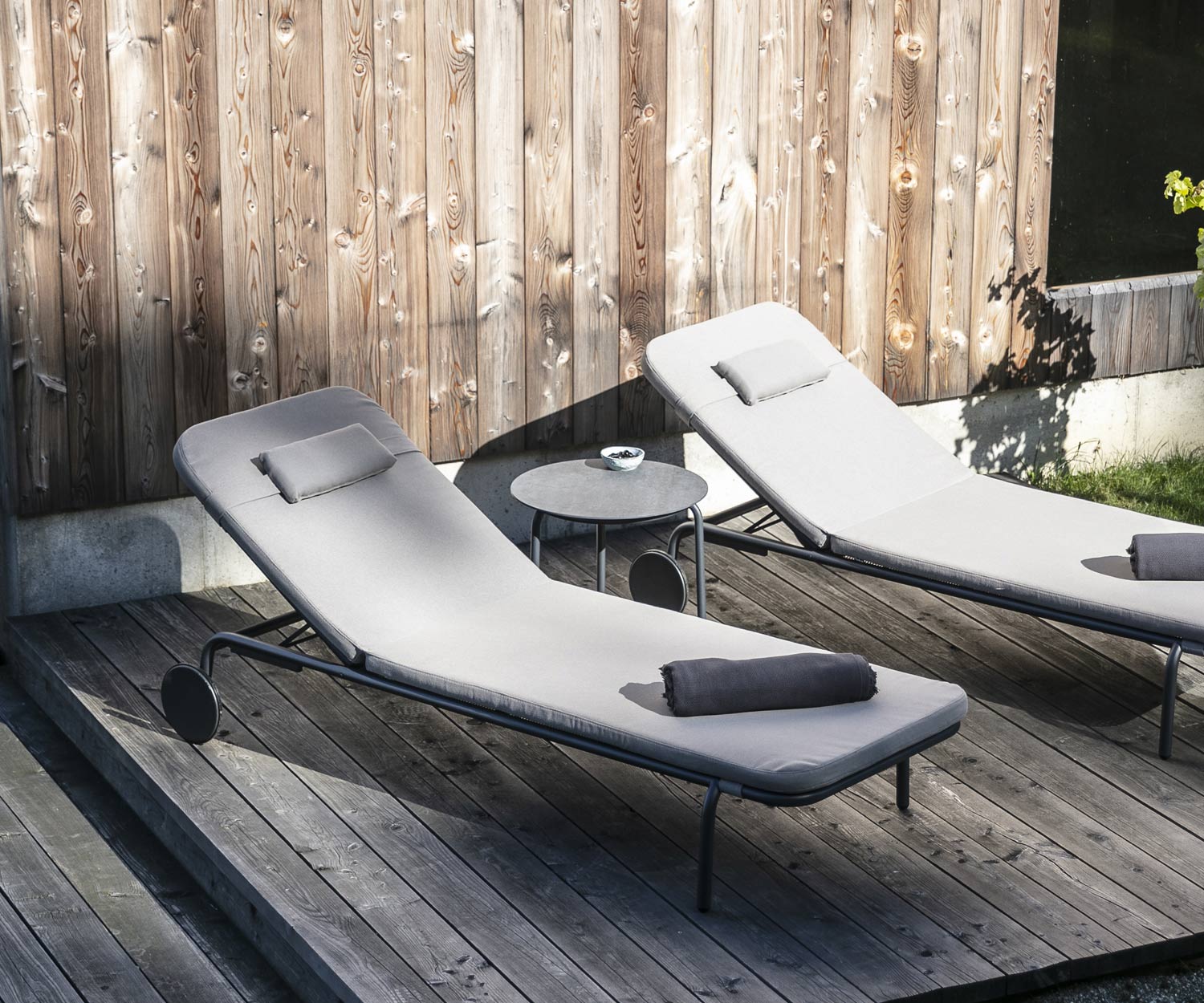 Table d'appoint design Starling de Todus avec deux chaises longues de jardin sur véranda en bois Table d'appoint design Starling de Todus avec deux chaises longues de jardin sur véranda en bois